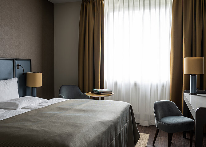AMERON Bonn Hotel Königshof Zimmer Deluxe Doppelzimmer Comfort Premium Bett Seitlich Schreibtisch Lampe Fenster mit Blick auf den Rhein